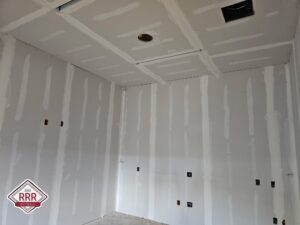 Sheets of drywall installed in a room remodel, ceiling sheetrock installed, tape and floated.
