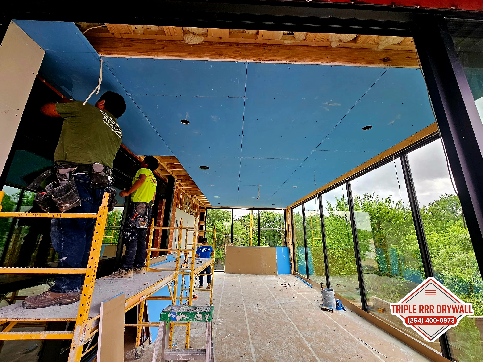 Drywall installer hanging Sheetrock panels in a Central Texas remodel